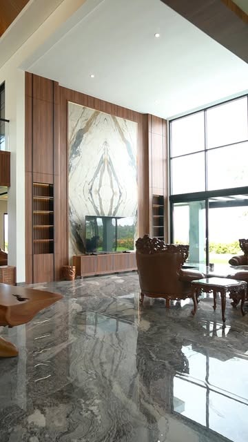 Ruang keluarga double-height dengan dinding marmer dan panel walnut